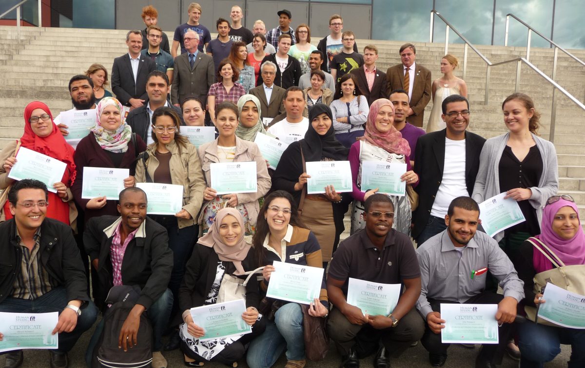 Group photo of students on stairs, holding their diplomas