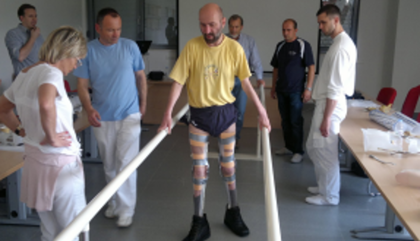 a patient in bilateral orthoses with examination board standing around and observing