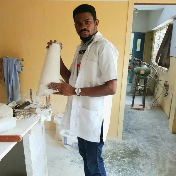 a student standing in a workshop and holding a plaster cast