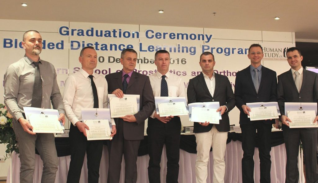 students standing with diplomas at graduation ceremony