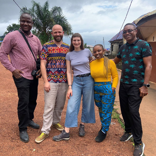 Five people posing for a picture outside